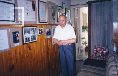 G. S. Chervo junto a sus fotos y diplomas