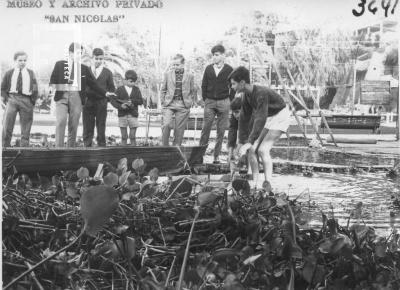 Club de Regatas. Jóvenes junto a canoa y camalotal