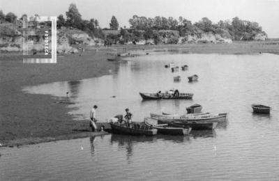 Canoas en la costa y barranca al fondo