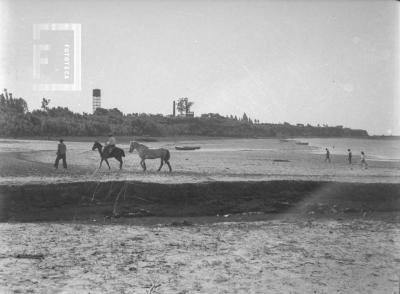 Zona del Balneario, con gente y caballos. Al fondo tanque Aguas Corrientes