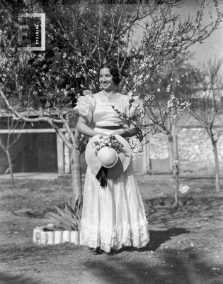 Dama con vestido largo y sombrero en mano