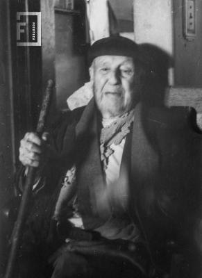 Anciano sentado con boina y bastón