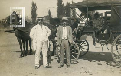 Dos hombres junto a carruaje con niños