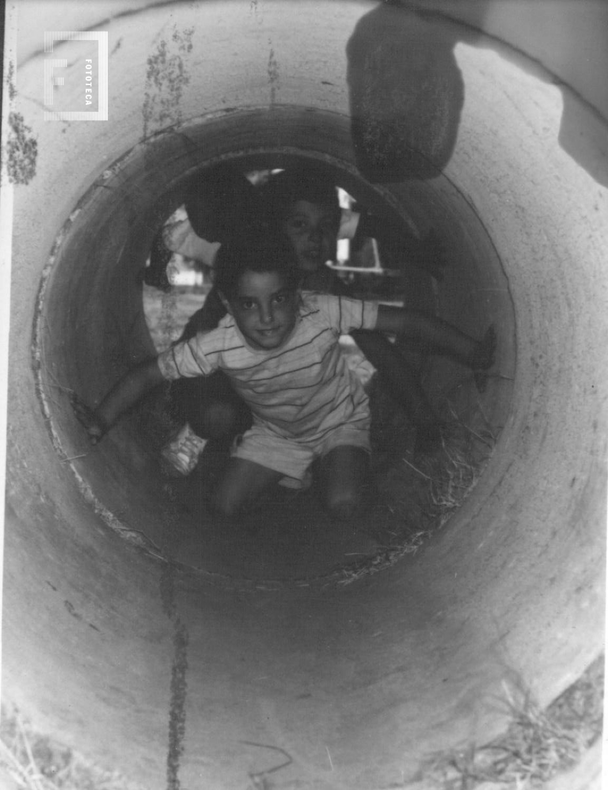Niños asomados en tubo de hormigón - Escuela de verano