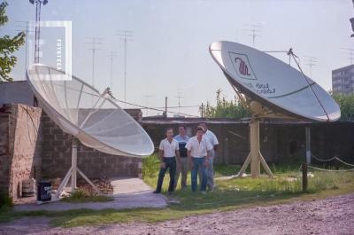 Personal y directivo de Canal 2 junto a parábolas de recepción satelital