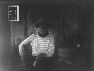 Don Guillermo Hoyo (Hormiga Negra) sentado, de frente, remera a rayas