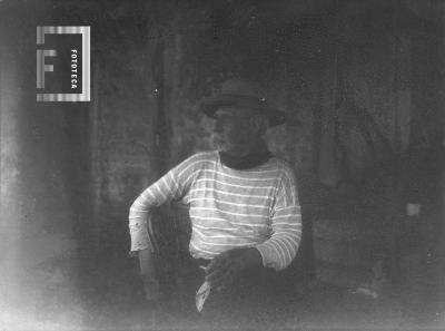 Don Guillermo Hoyo (Hormiga Negra) sentado, rostro de perfil, remera a rayas