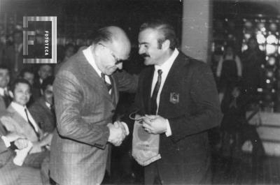 G. S. Chervo recibiendo del Pte. de la Agrupación de Estudiantes del CENMA Nº 3, Sr. Luis A. Lamberti, una medalla y banderín de la 1ra. Promoción de Bachilleres